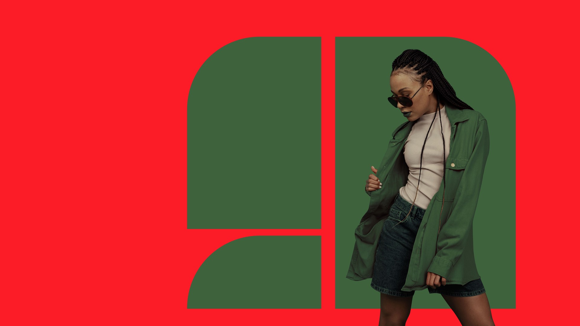 Fashionable young woman wearing green coat and sunglasses posing confidently on bold red and green background.
